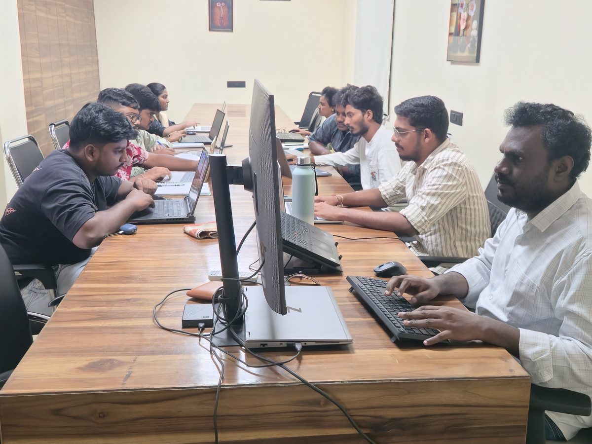 Students at laptops along the long table in the Ameerpet training room