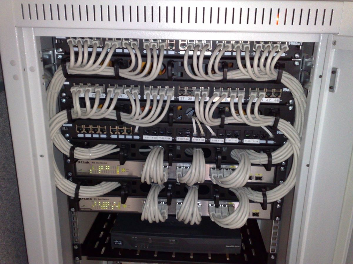 A rack of Ethernet switches and patch panels with white cables